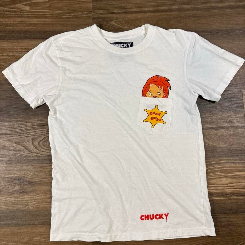 White Chucky tee with red-haired cartoon character and yellow sheriff's star
